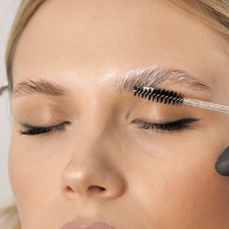 before and after photos of an eyebrow lamination. In the before, many of the hairs go downwards and there are empty patches. The after shows full fluffy brows using the existing hair to cover the bare patches.